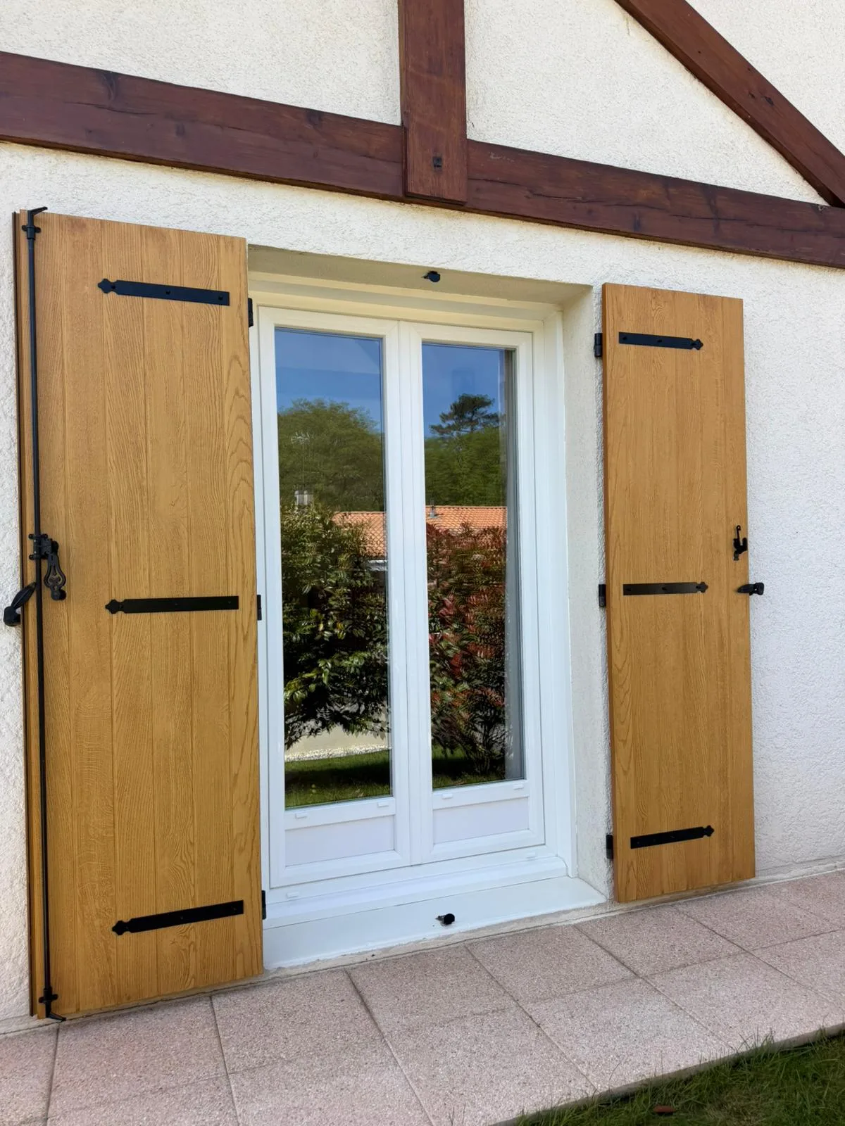 Volets battants chêne clair sur une fenêtre traditionnelle