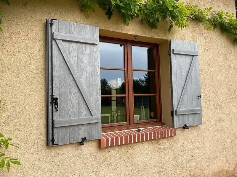 Volets battants gris sur une façade ocre