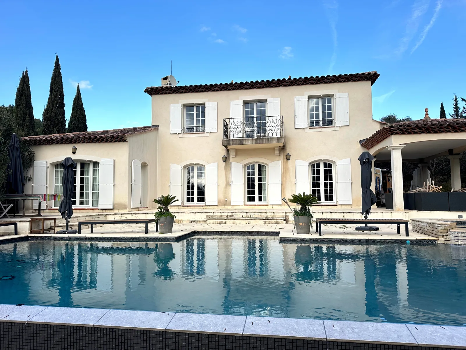 Maison avec volets blancs autour d’une piscine