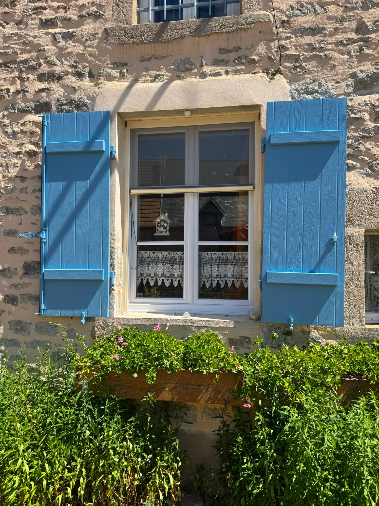 Volets battants bleus sur une façade en pierre