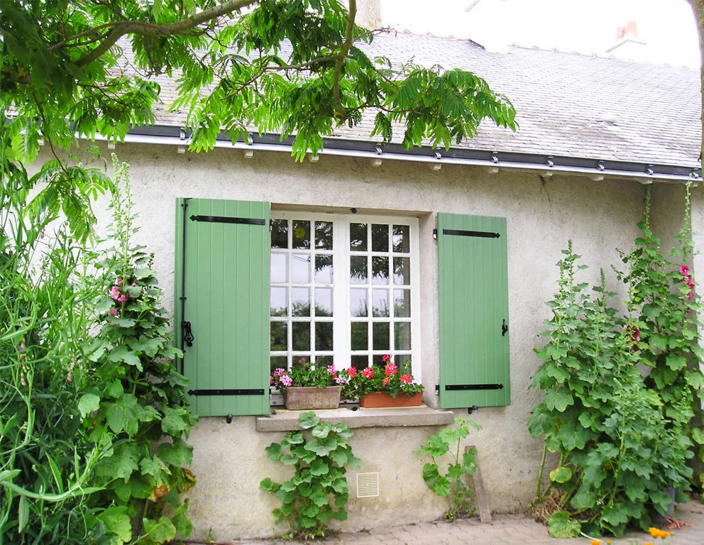 Volets battants verts dans un jardin fleuri