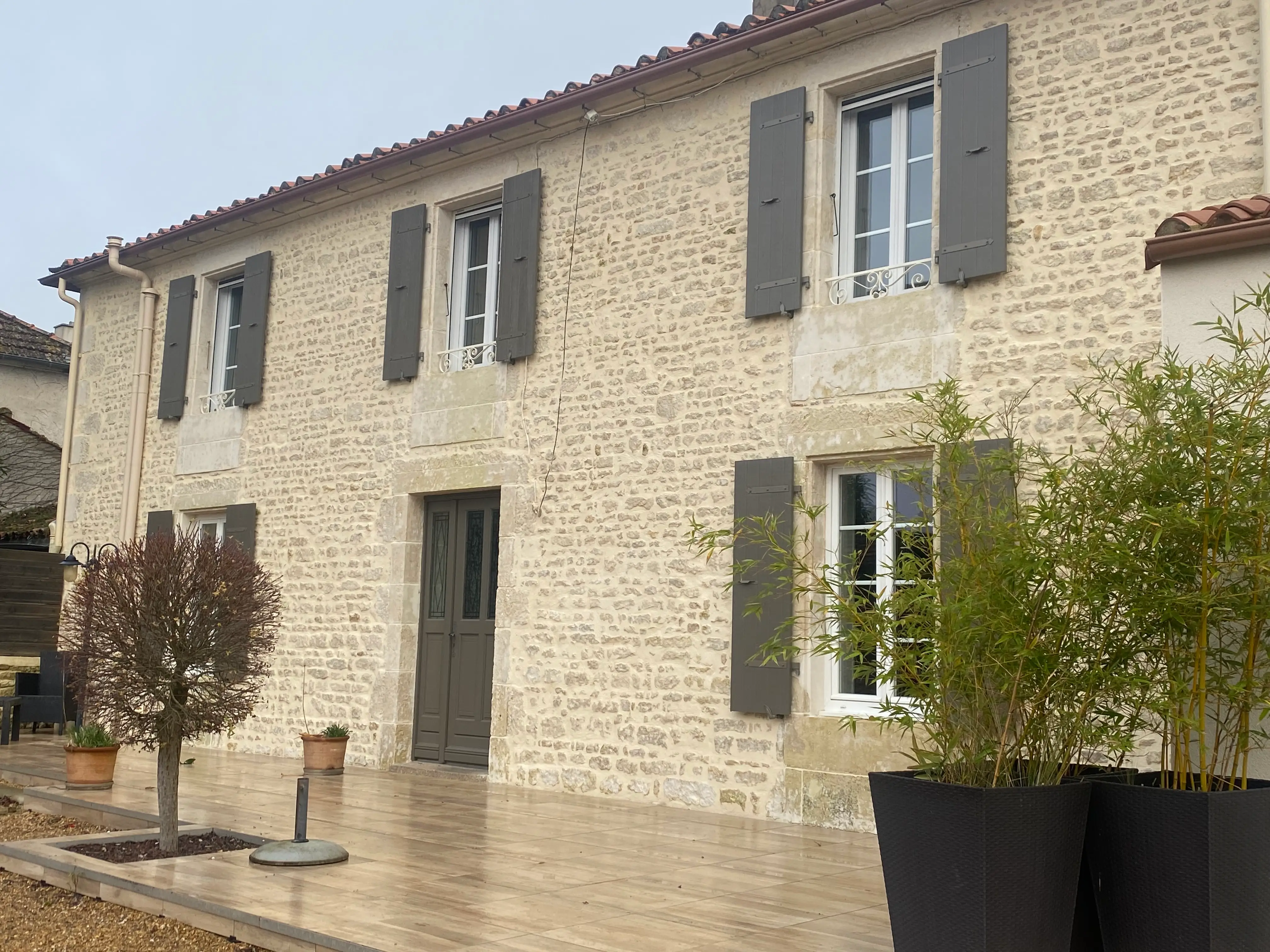 Façade en pierre avec volets gris ouverts